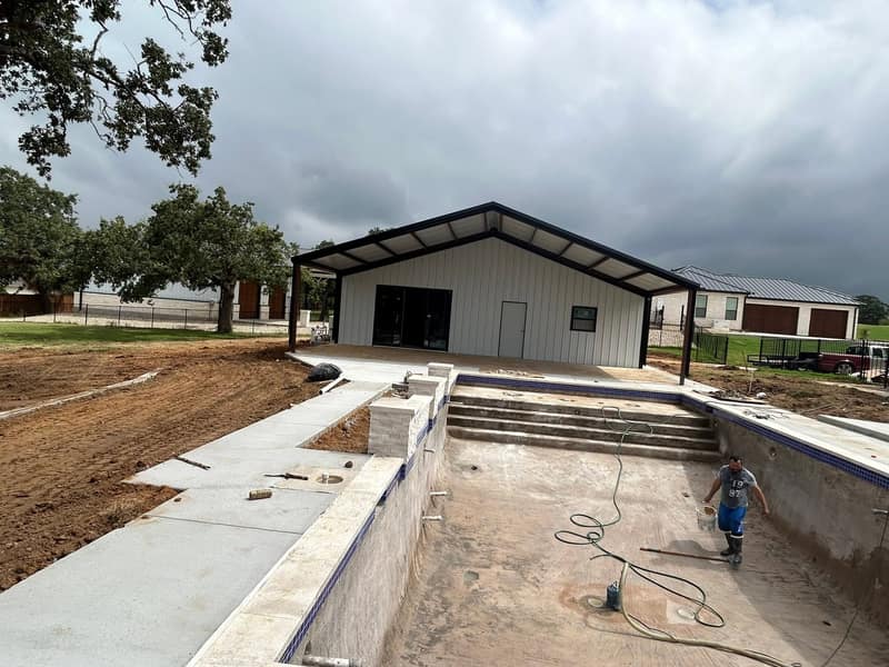 White metal pool house with a covered patio, the pool shell being finished in front