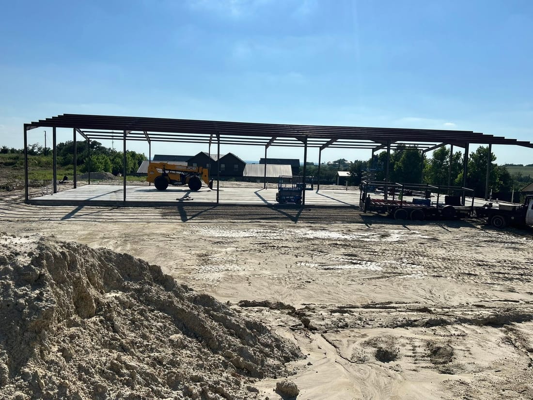 Steel frame of a workshop standing on a freshly poured concrete slab